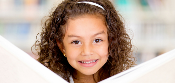 Girl looking up from book smiling